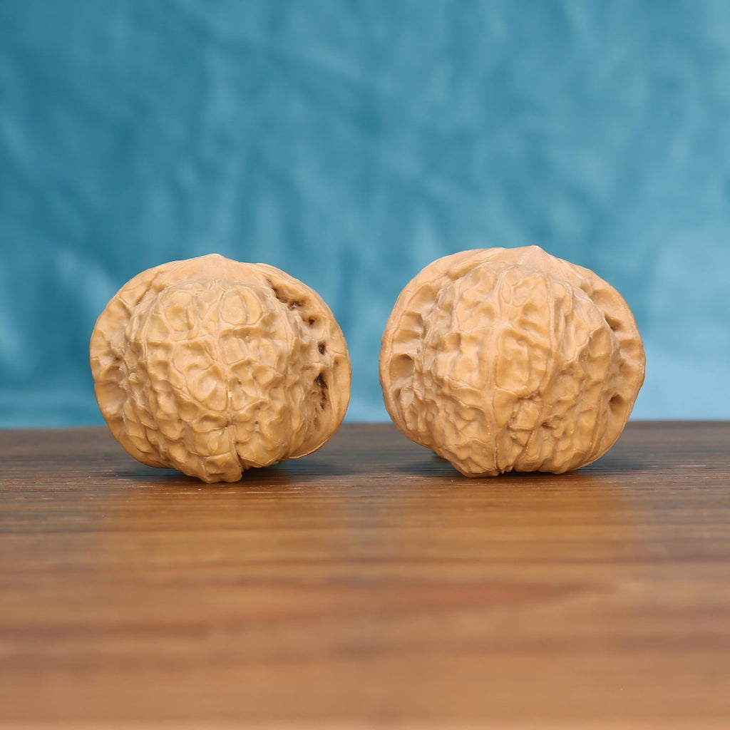 Two Nan-Gua-Dun wenwan walnuts on wooden surface, blue fabric background – matching earthbound bastion set
