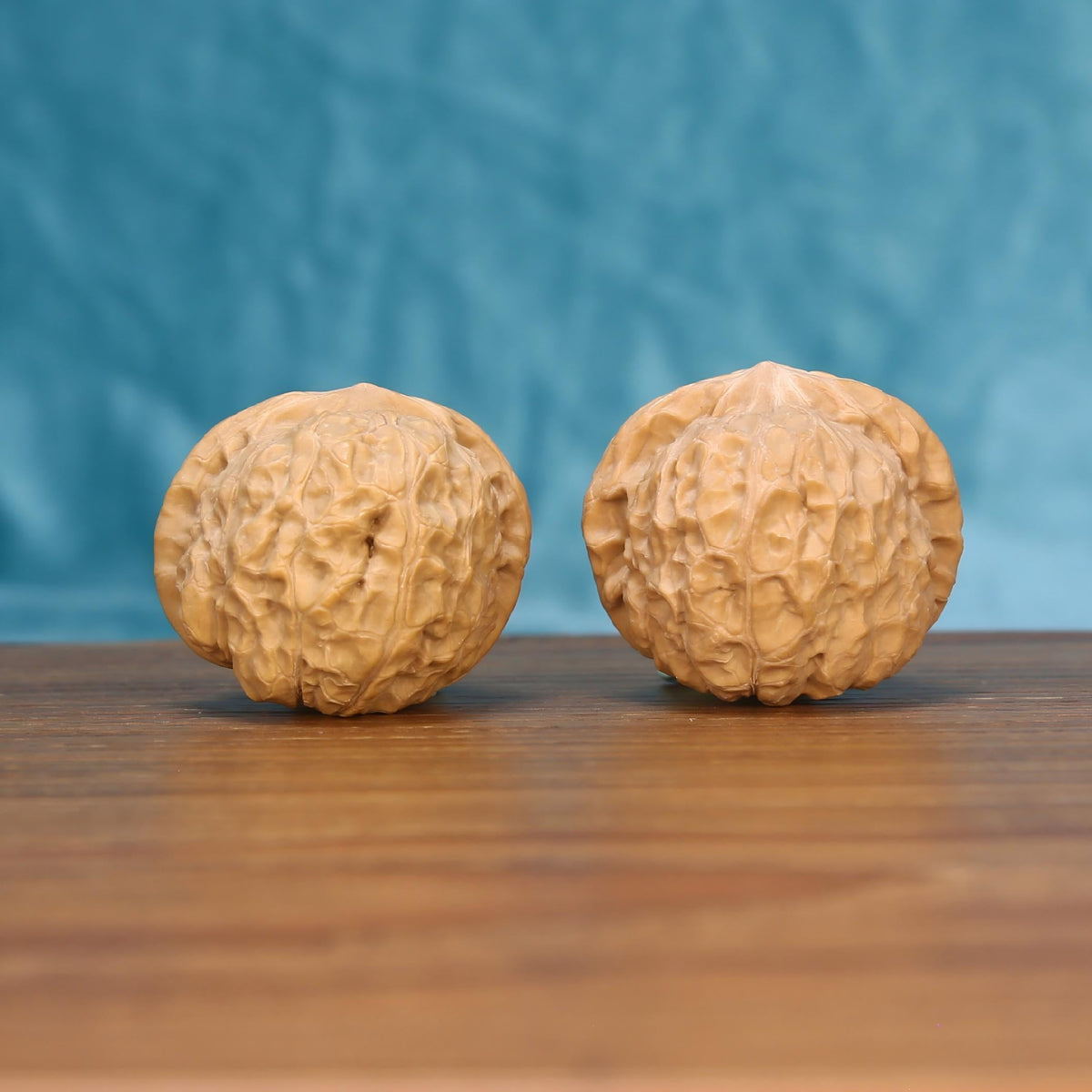 Nan-Gua-Dun walnut set side profile on wood, blue background – pumpkin-shaped squat grain detail
