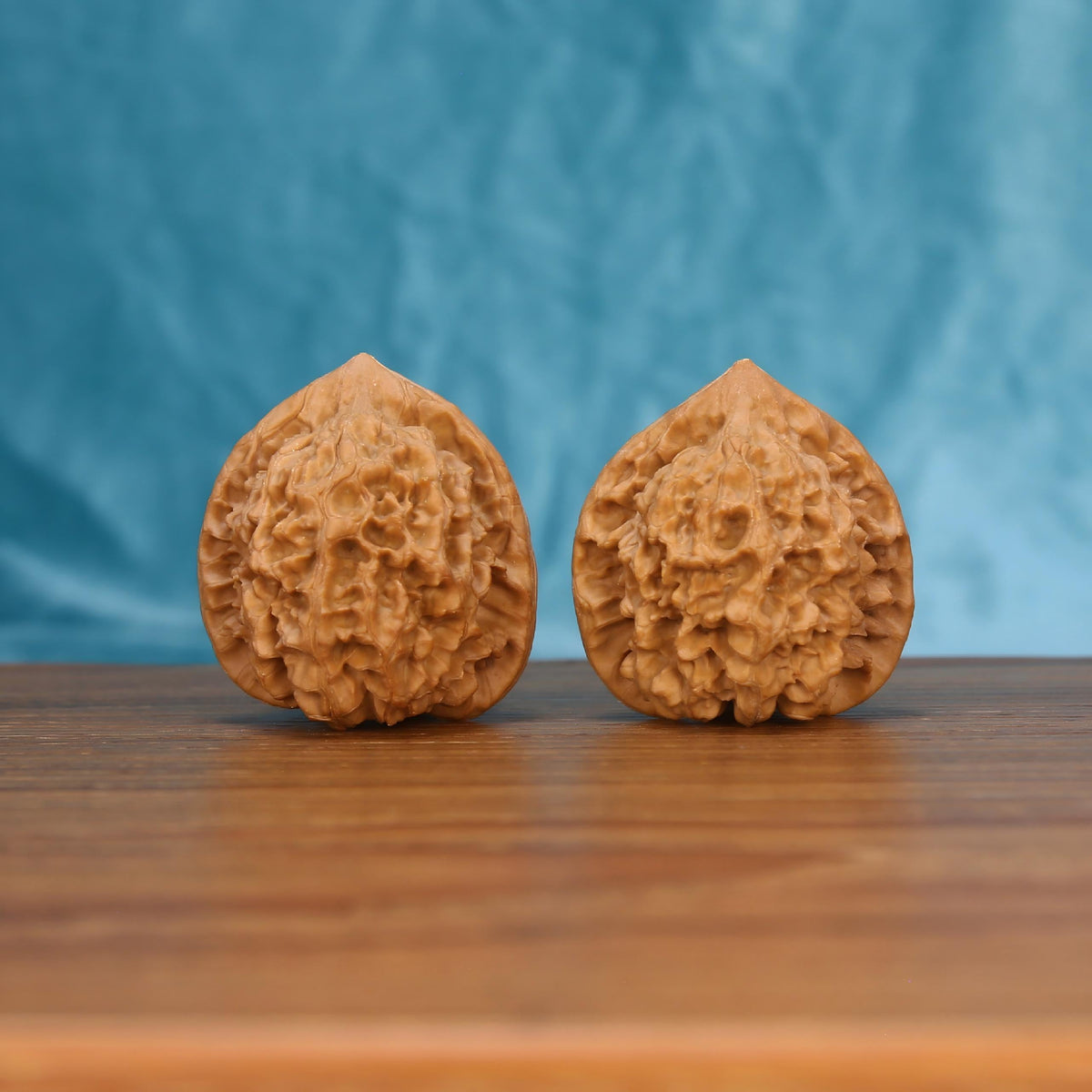 Qi-Lin-Wen Guan-Mao walnut set side profile on wood, blue background – qilin-pattern crown grain detail