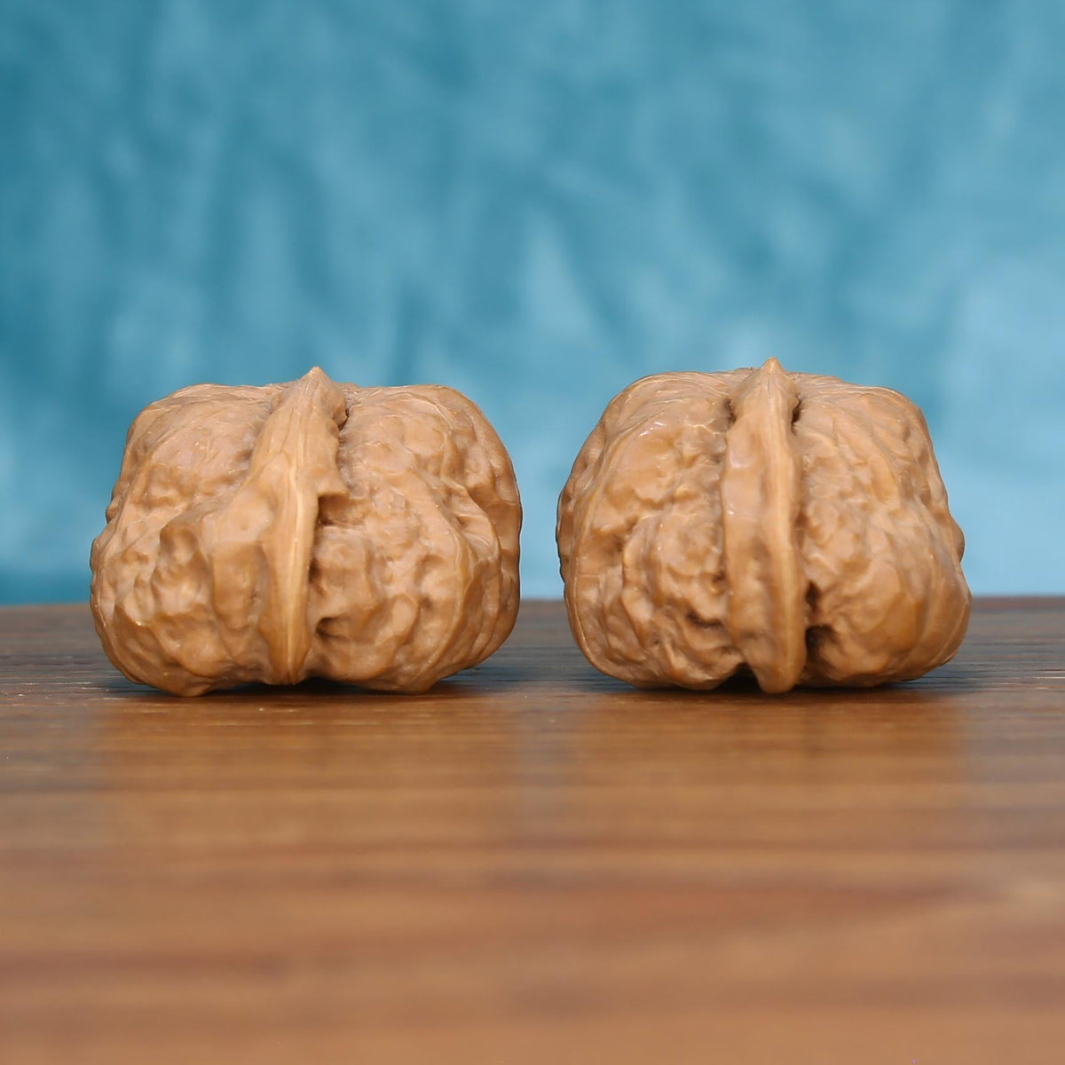 Two Yi-Dao-Jin wenwan walnuts on wooden surface, blue fabric background – matching singular spine set