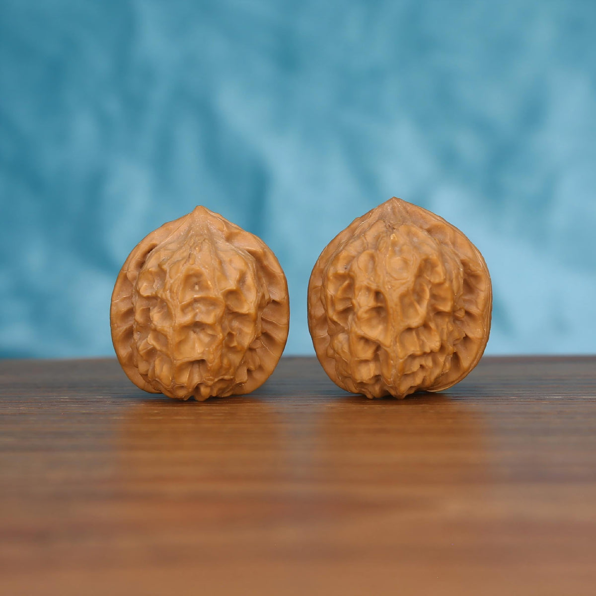 Pair of wenwan walnuts with deep carved texture, upright front view on wooden surface